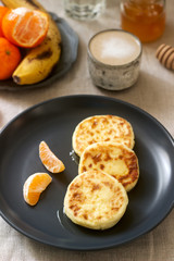 Vegetarian breakfast of quark pancakes with honey, fruit and coffee with milk. Rustic style.