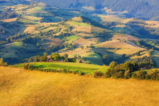 Beautiful valley with small wooden houses and pastures in Transylvania