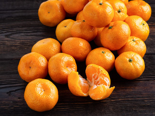 Clementines or mandarines on dark brown wooden background.