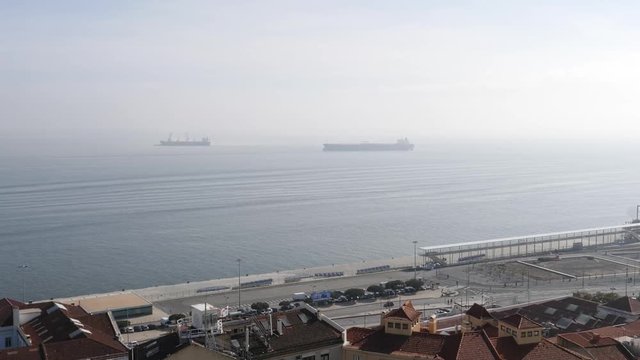 Aerial view over rooftops of houses with port, transportation ships tankers with crane and large industrial area near Terminal de Cruzeiros de Lisboa