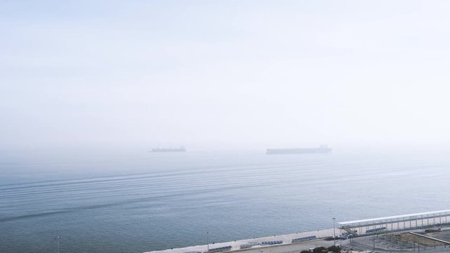 Cinematic aerial view over rooftops of houses with port, transportation ships tankers with crane and large industrial area near Terminal de Cruzeiros de Lisboa
