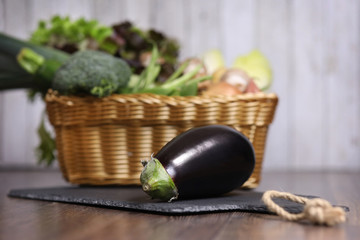 Aubergine liegt vor einem Korb mit Gemüse