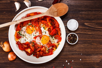 Shakshuka - fried eggs with vegetables in frying pan