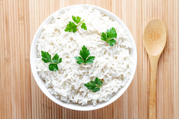 Bowl with white boiled rice with green fresh parsley for delicious healthy lunch. Cereal food and dishes. Top view