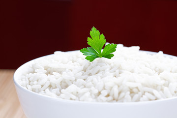 Bowl with white boiled rice with green fresh parsley for delicious healthy lunch close up. Cereal food and dishes.