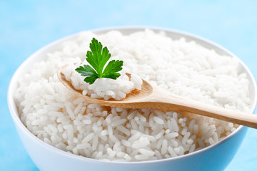 Bowl with boiled rice with green fresh parsley for delicious healthy lunch on a blue background close up. Cereal food and dishes.