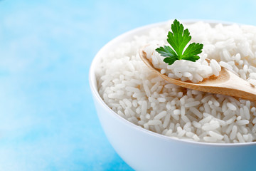 Bowl with boiled rice with green fresh parsley for delicious healthy lunch on a blue background. Cereal food and dishes. Copy space