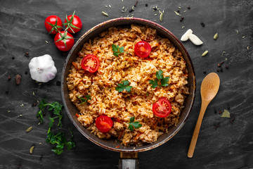 Homemade delicious pilaf with chicken, fresh parsley and ripe vegetables in a pan for lunch on a...