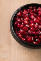 Rote Granatapfel Kerne in schwarzer Porzellan Schale auf Holz Hintergrund