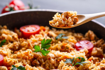 Full pan of homemade delicious pilaf with chicken, fresh parsley and ripe vegetables close up