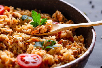 Full pan of homemade delicious pilaf with chicken, fresh parsley and ripe vegetables close up