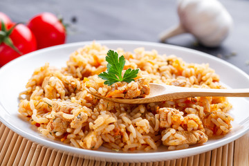 Plate of homemade delicious pilaf with chicken, fresh parsley and ripe vegetables for lunch
