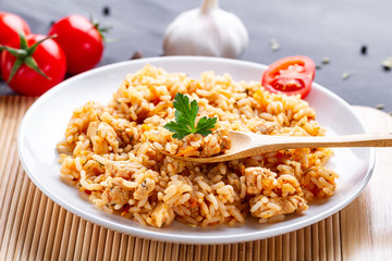 Plate of homemade delicious pilaf with chicken, fresh parsley and ripe vegetables for lunch