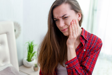 Fototapeta na wymiar Young woman suffering and experiencing strong aching toothache. Tooth decay and sensitivity. Diseases gums