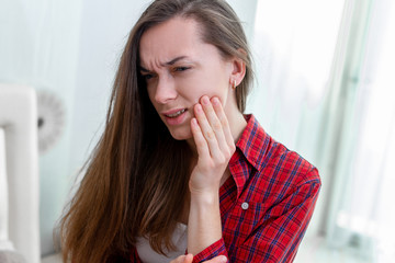 Young woman suffering and experiencing strong aching toothache. Tooth decay and sensitivity....