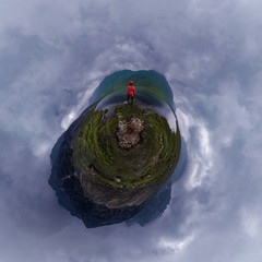 man stands by lake in red jacket in cloudy weather. tiny planet 360
