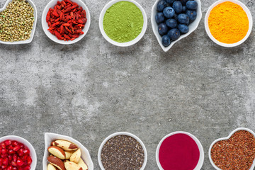 various superfoods on gray background. Superfood as chia, matcha, acai, turmeric, nuts, seeds, goji, blueberry.