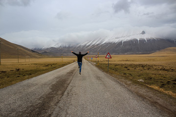 Obraz premium Happy man jumping in the middle of a mountain road