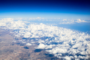flight above the clouds. The shadows of the clouds on earth. Blue horizon