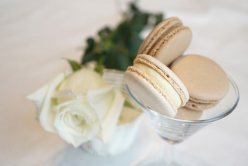 White and cream milk cheese macarons in wine glass with white rose flower