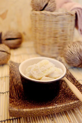 Banana in coconut milk, popular dessert from fruit, Thai style home made dessert in a cup on wood mat served after meal or appetizer, popular street food of Thailand