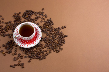polka dot coffee cup and coffe beans mess on a brown background free space for text