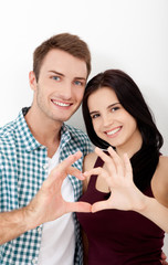 Playful couple fooling on valentine day. Beautiful young lovers are joining and smiling, making a heart frame from their hands isolated on white background
