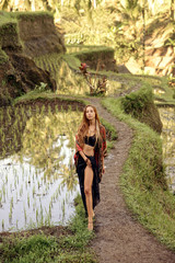 beautiful woman with red hair in casual clothes walking by rice terraces in Bali