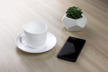 coffee cup, succulent and smartphone  on a wooden table