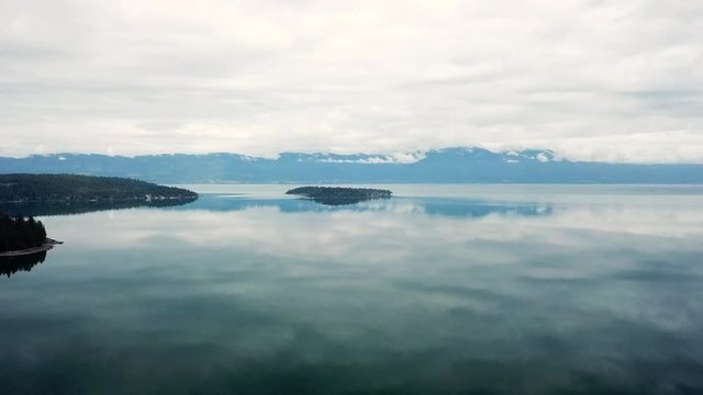 Aerial Forward Slow: Island Lake of Flathead Surrounded by Water Reflections