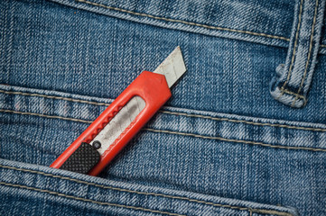 closeup of orange cutter in blue jeans pocket
