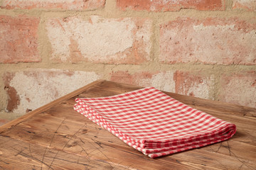 Empty wooden table with tablecloth over brick stone wall background.