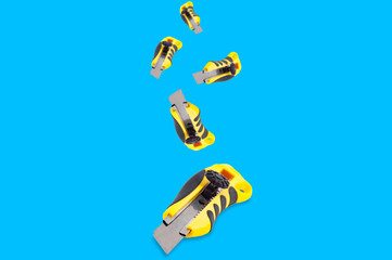 Falling stationery knives with yellow and black plastic handle on blue background