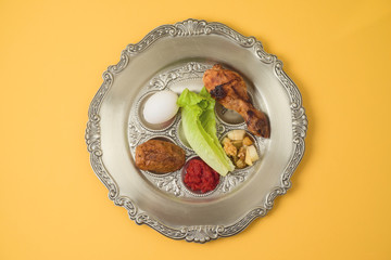 Jewish holiday Passover celebration concept with traditional seder plate on yellow background.