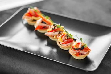 Delicious appetizer with ham, cheese, pepper and tomato in tartlets. Concept of food, restaurant,...