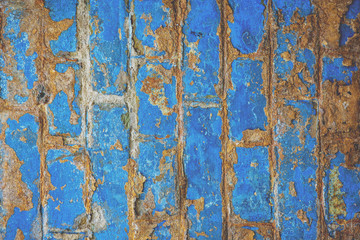 Old blue painted brick wall background with peeling paint