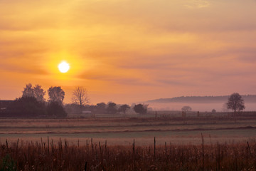 Sunrise in the field in the early misty morning. Rural landscape