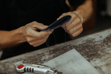 Close up of leather craftsman working with natural leather and tools. Handmade master at work in local workshop. Leather wallet stitch.