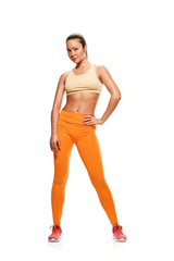 Beautiful young woman bodybuilder in sportswear posing on white background