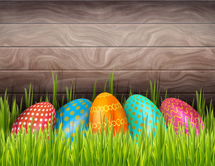 Happy Easter wooden background with colorful painted eggs and green grass. Horizontal banner with copy space.