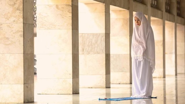 Religious muslim woman praying inside the Istiqlal Mosque in Jakarta, Indonesia.