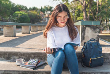 Pretty relaxed young woman reading a book at the lawn with sun shining