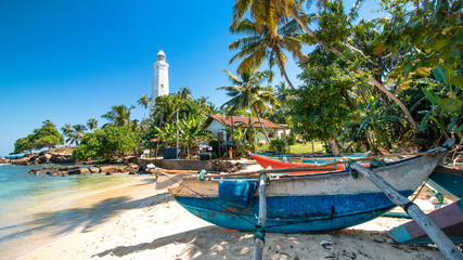 boat on a beach with a lighthouse in sri lanka