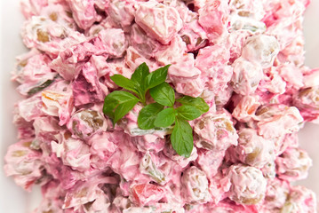 Salad from marble potatoes and beetroot mixed with mayonnaise and decorated with fresh basil leafs in a white on a white plate, Philippines