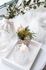 Interior tray decoration with burning candle, mimosa flowers and branches