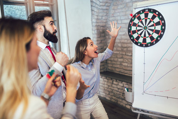 Business people making team training exercise during team building seminar, play darts. Indoor team...