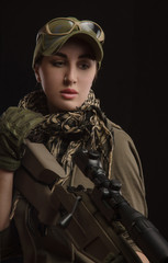 the girl in military special clothes posing with a gun in his hands on a dark background in the haze