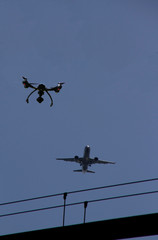 Drone in the sky near airport with approaching airplane