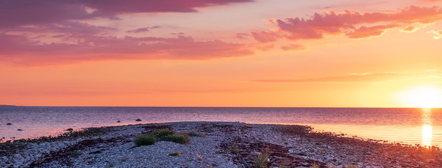 Panorama sunset over a stone beach with a dramatic colors and clouds. Hittarps revet is an unknown beauty in Helsingborg, Sweden. 