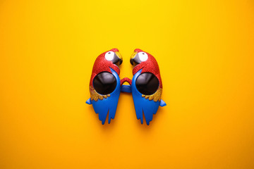 Glitter ara parrots sunglasses on the bright yellow background. Summer party concept. Minimal composition. Flat lay. Top view. © Intergalactic Rada